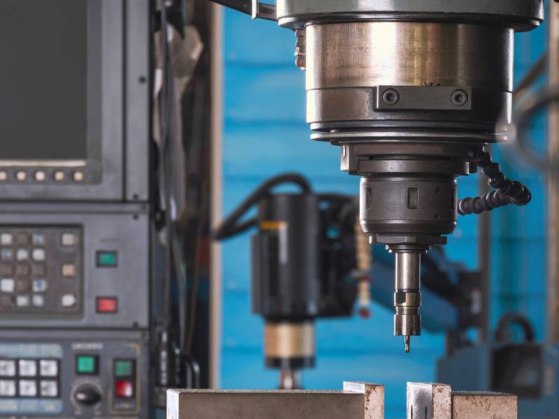 Close up of CNC milling machine tool with mill in chuck preparing to  process metal detail in manufacturing workshop area